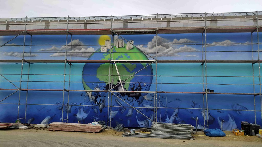 Malowanie planety ziemi, mural przedstawiający planetę Ziemie pływająca w morzy pełnym zużytego plastiku