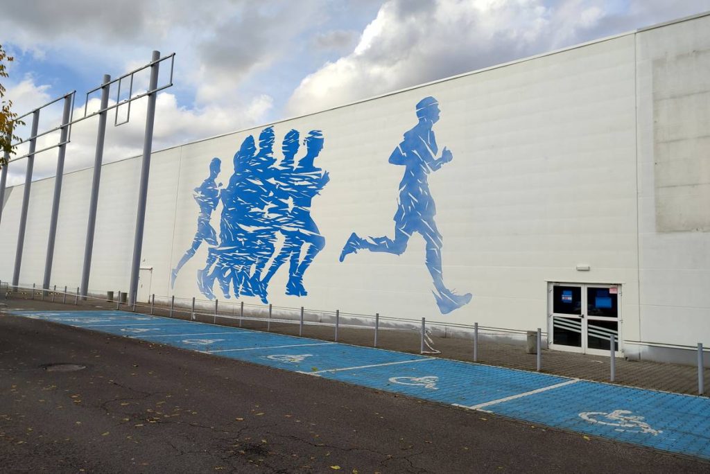 Mural sportowy dla Decathlon w Poznaniu, malowanie biegaczy, mural promujący sportowy tryb życia