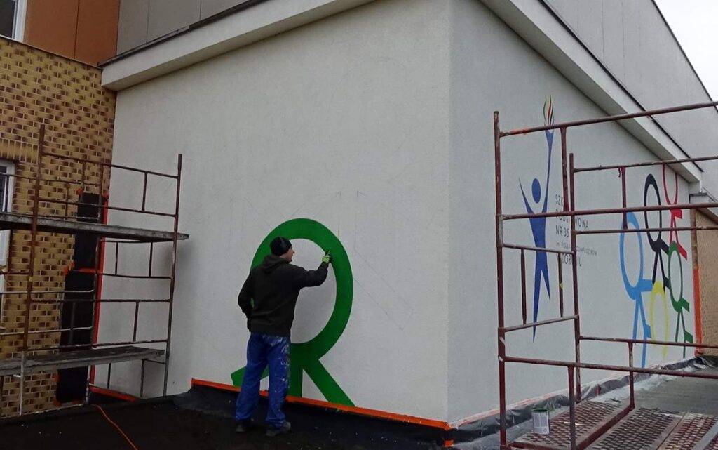 Malowanie logotypu na ścianie w szkole w Toruniu, malowanie murali i logotypów